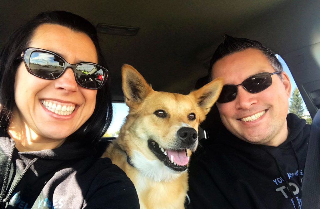 Robyn and Gavin with their dog driving in their car. A big smiles on everyone's face!