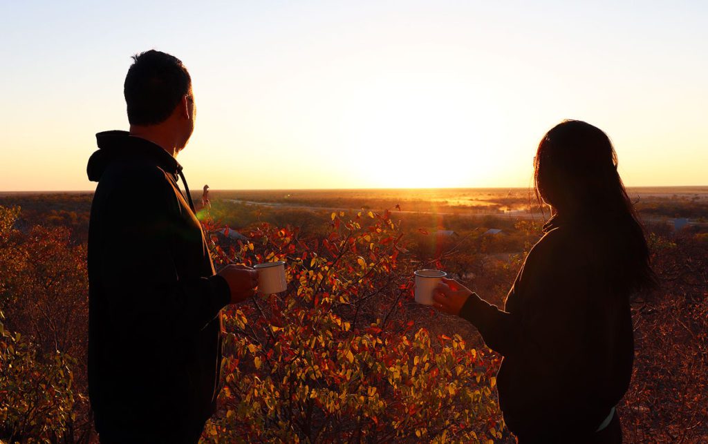 Robyn and Gavin drinking coffee and watching the sun rise over the Etosha National Park in Namibia.