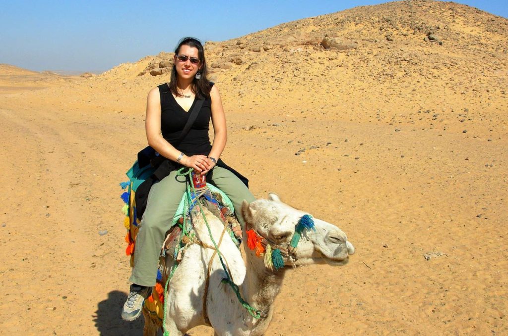 Robyn riding a camel outside in the Egyptian desert.