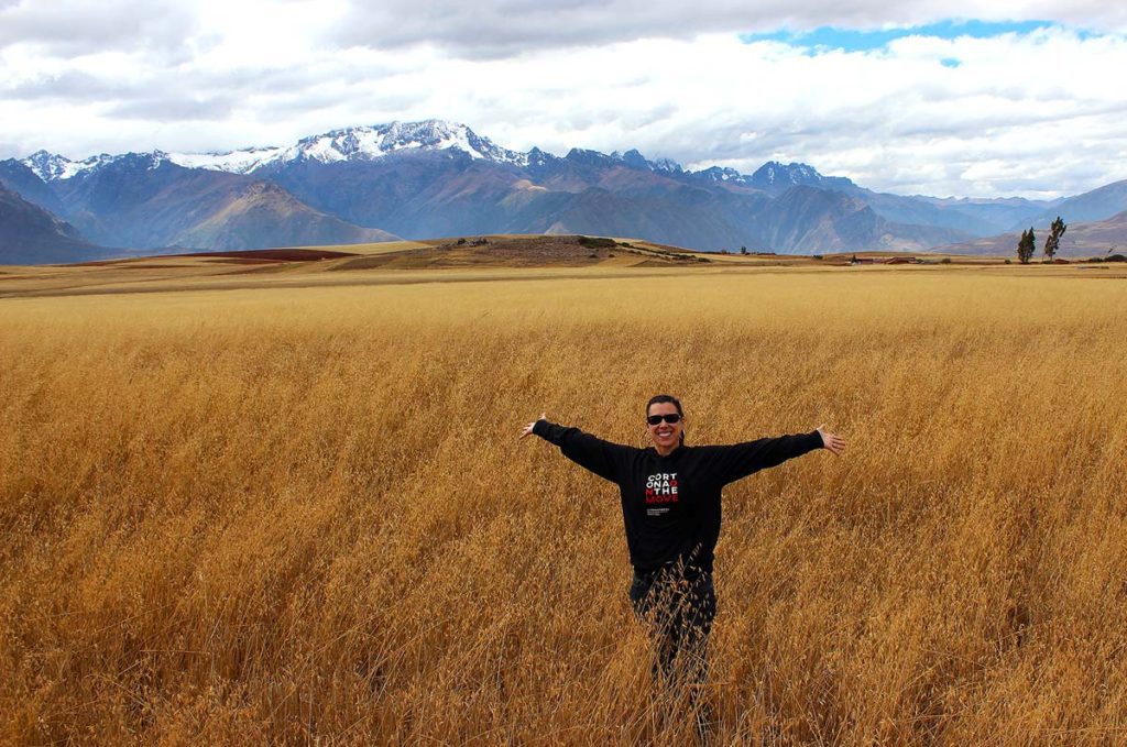 Robyn standing with open arms in front of the Andes Mountains in Peru.