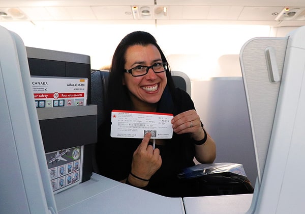 Robyn smiling and holding her flight ticket seated in first class on our way to Greece! This was the first time we flew first class!