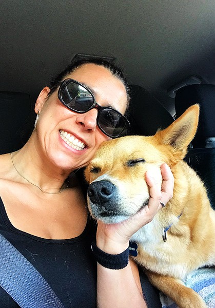 Robyn cuddling with her dog, Leonardo, in our SUV, wearing Motion Sickness Wristbands.