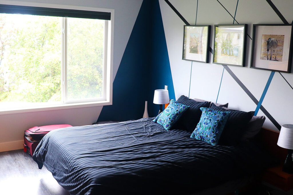 Bedroom with a large window. Bed has a weighted blanket on top, one strategy included in my anxiety toolbox.