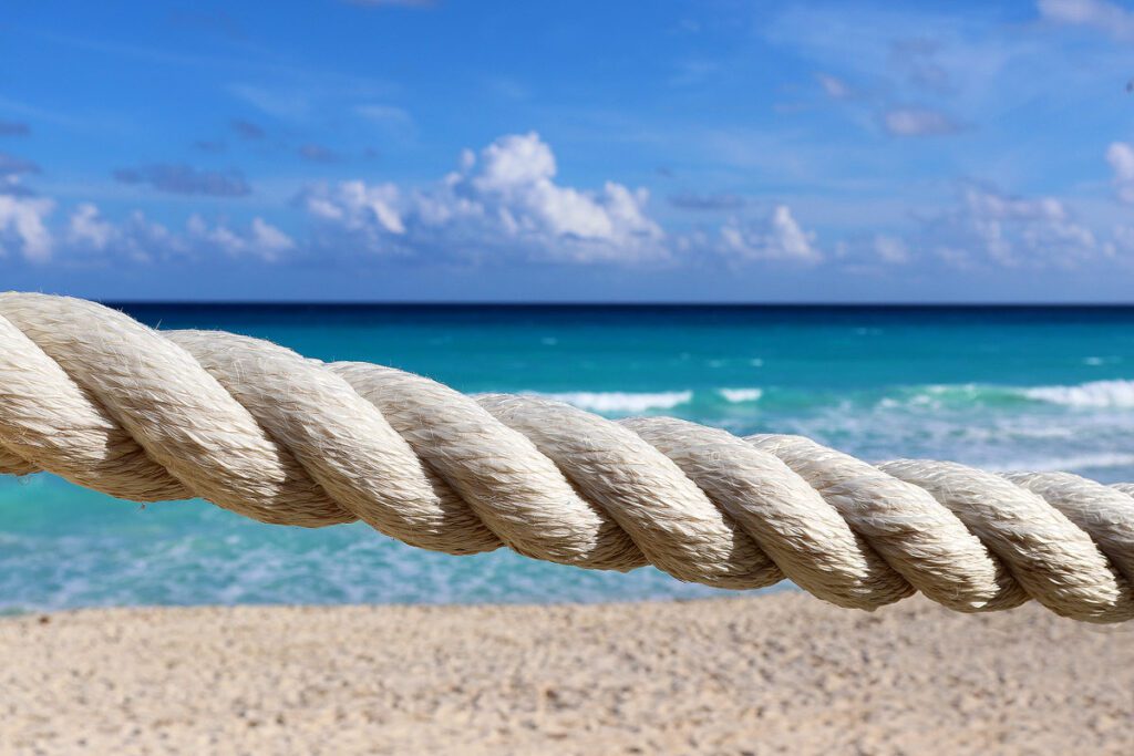 A white rope hanging in front of the turquoise water and white sand beach of Cancun.