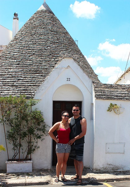 Robyn and Gavin posing in front of a door on one of the famous trulli houses with a cone shaped roof.