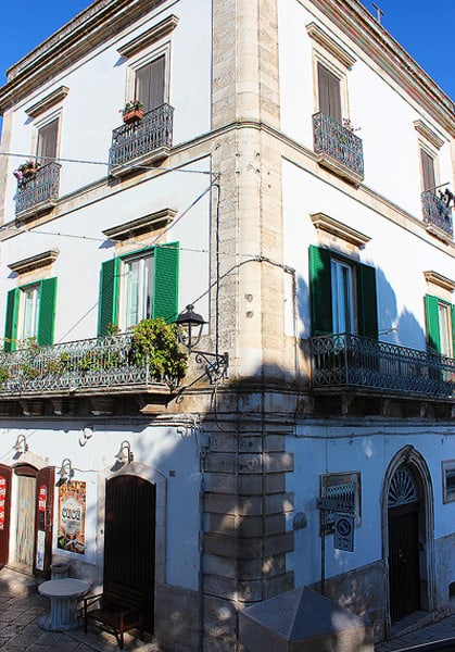 A close up view of a white building with green shutters.