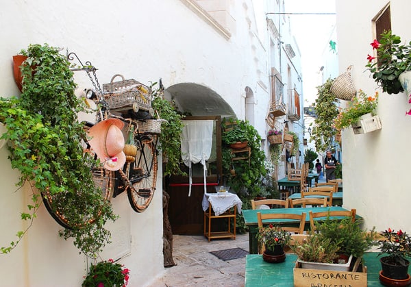 A romantic restaurant in a tiny alleyway, decorated with antiques and green plants.