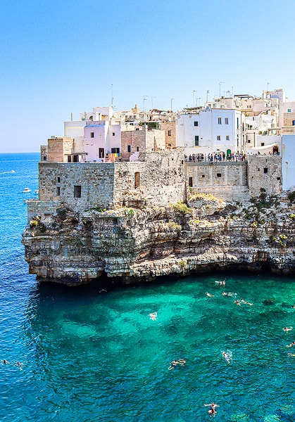 The town of Polignano a Mare is built on the edge of the cliffside. The gorgeous turquoise water with people swimming underneath.