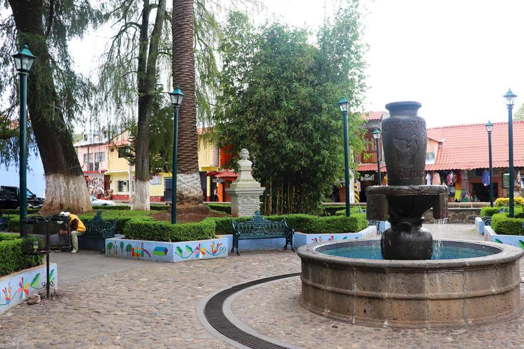 A circular fountain surrounded by tall trees in the centro of Huasca de Ocampo.