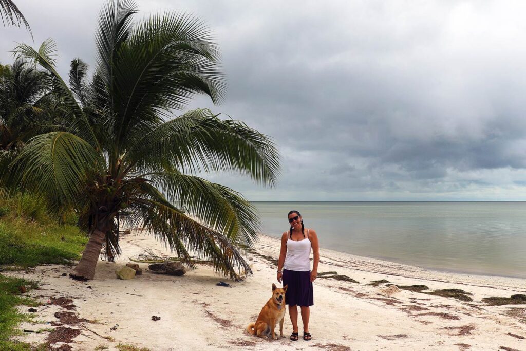 Robyn and her dog standing on an empty beach in Mexico.