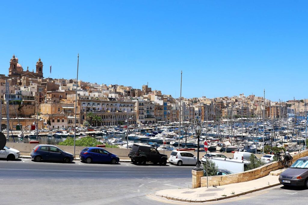 Parked cars on a street that leads to the harbor of the 3 Cities. Finding parking can be challenging when driving in Malta.