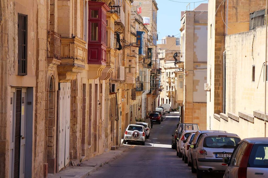 A photo of cramped parked cars on a narrow street in Malta.