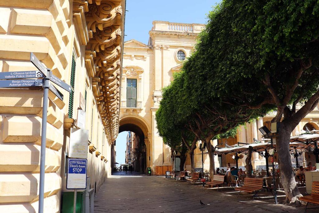 A quiet, narrow street in Valletta lined with beautiful green trees opposite the police station.