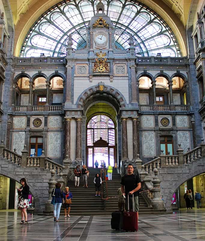 Gavin standing in the gorgeous Antwerp train station. There are two staircases arching down at either end and beautiful stained glass above.
