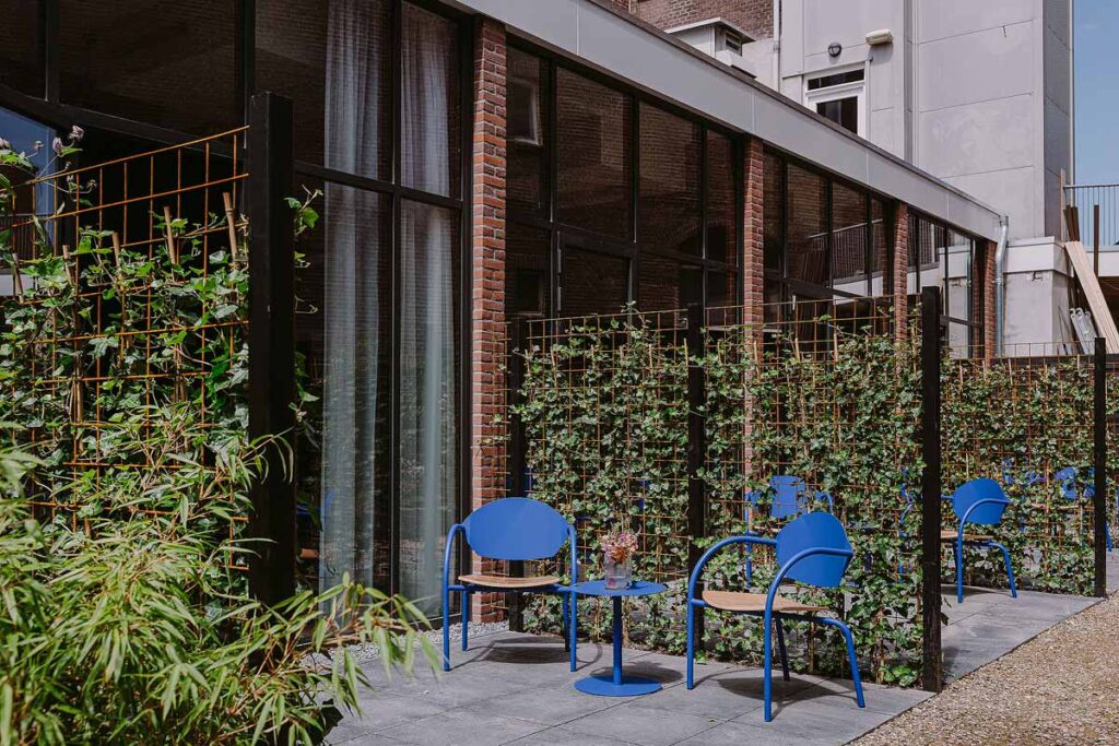 The Supernova Hotel in Rotterdam showing a private terrace with direct access to the garden. There are 2 blue chairs and floor to ceiling windows into the suite.