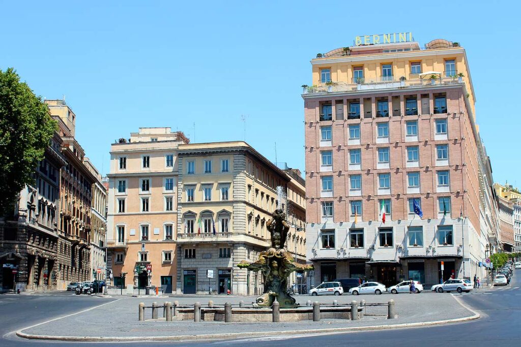 Staying in a quaint piazza while on an accessible trip to Rome will help you explore the city. There is a pretty fountain in the center with tall colorful buildings behind.