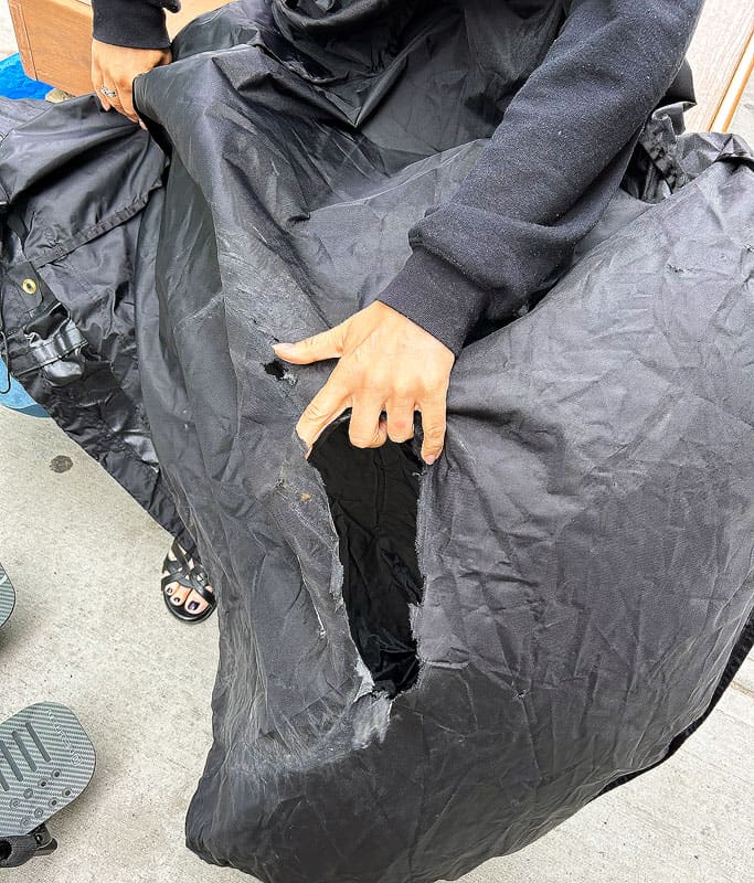 My black torn wheelchair cover that was damaged from a flight. My hand is holding open the large tear in the fabric as evidence for my claim. It's important to know your rights when flying with a wheelchair.