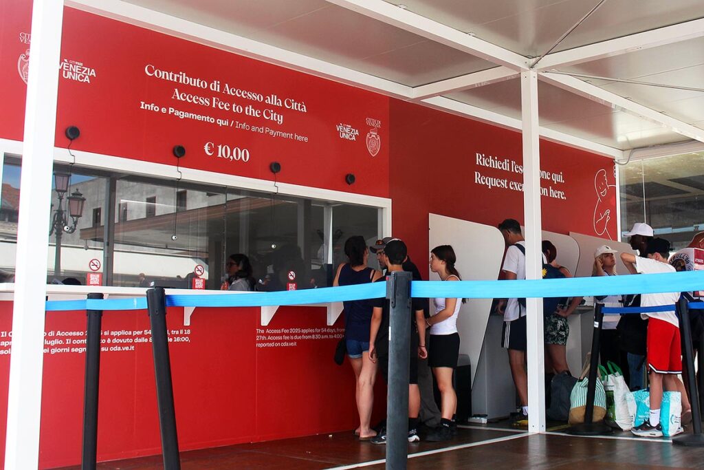 People in line paying the Venice Day Tax at a bright red kiosk near the train station. This is required for anyone spending one day in Venice.
